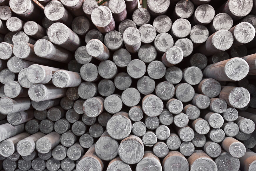 Conducte din oțel fără sudură sunt produse prin încălzirea și întinderea pieselor de oțel solide, apoi prin străpungerea lor pentru a prezenta centre goale A stack of solid steel billets